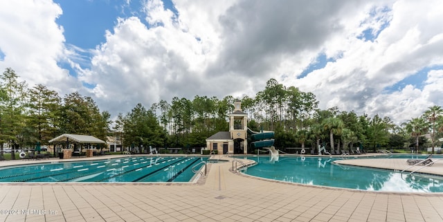 view of swimming pool with a water slide and a patio