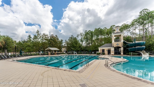 pool featuring a water slide, a patio, and fence