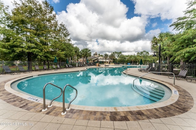 community pool with a patio and fence