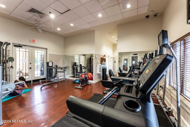 workout area featuring a paneled ceiling, a high ceiling, wood finished floors, visible vents, and french doors