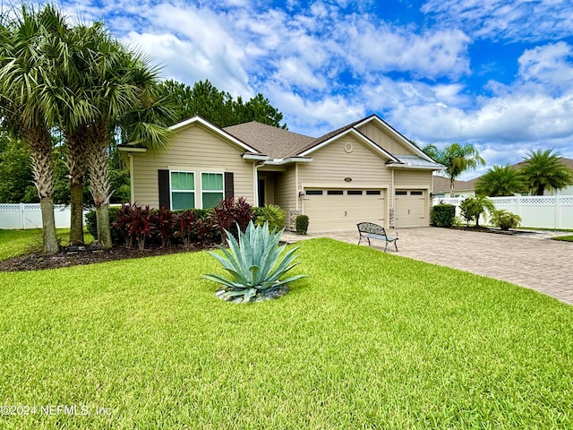 ranch-style home featuring a front lawn, decorative driveway, fence, and an attached garage