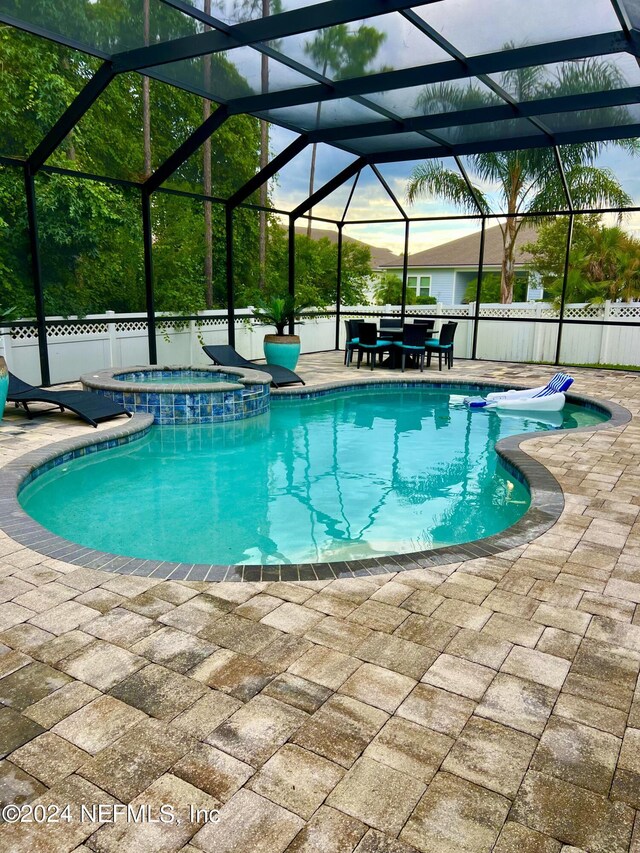 view of pool featuring glass enclosure, a patio area, and an in ground hot tub