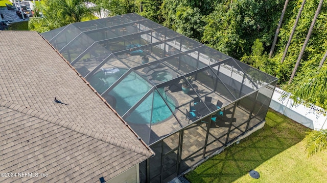 view of swimming pool with a lanai, fence, and a lawn