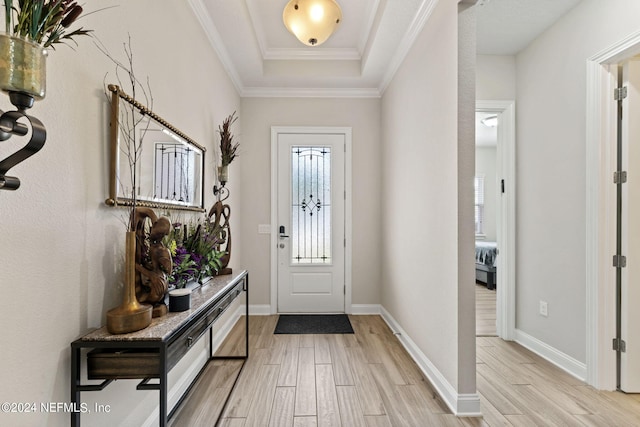 entryway with a raised ceiling, ornamental molding, and light hardwood / wood-style flooring