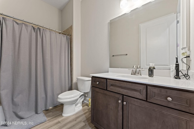 bathroom featuring toilet, a shower with shower curtain, wood finished floors, and vanity