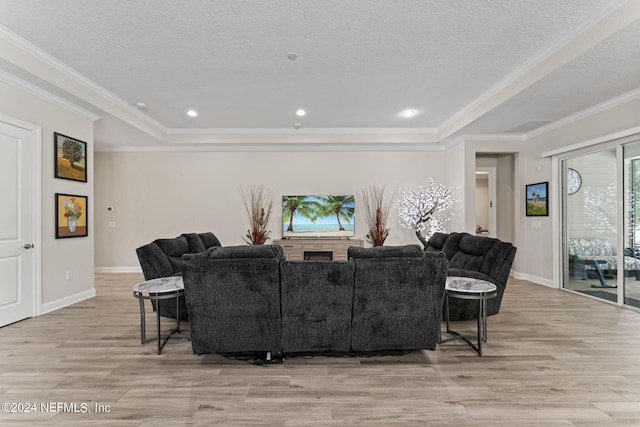 living room with a textured ceiling, ornamental molding, light wood-type flooring, and baseboards