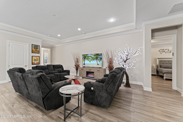 living room with a fireplace, light wood finished floors, visible vents, a textured ceiling, and baseboards