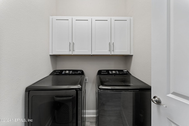 washroom featuring cabinet space and washer and clothes dryer