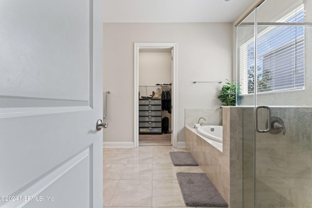 bathroom featuring a garden tub, a shower stall, baseboards, and a walk in closet