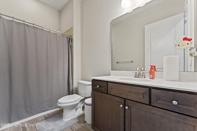 bathroom with toilet, curtained shower, wood finished floors, and vanity