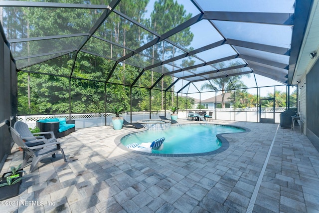 view of pool featuring glass enclosure, a patio area, and a pool with connected hot tub