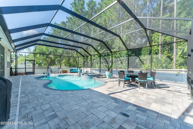 view of pool with glass enclosure, a pool with connected hot tub, and a patio