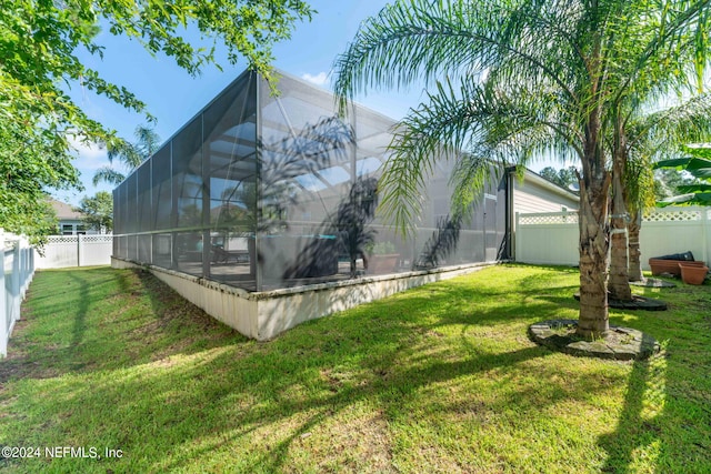 view of side of property featuring glass enclosure, a fenced backyard, and a yard