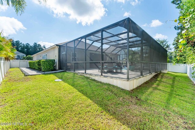 exterior space with glass enclosure, a yard, and a patio area