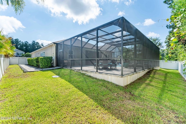 back of house featuring a yard, a patio area, a fenced backyard, and glass enclosure