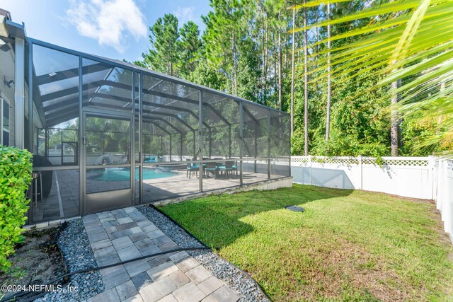 view of yard with glass enclosure, a fenced in pool, and a patio area