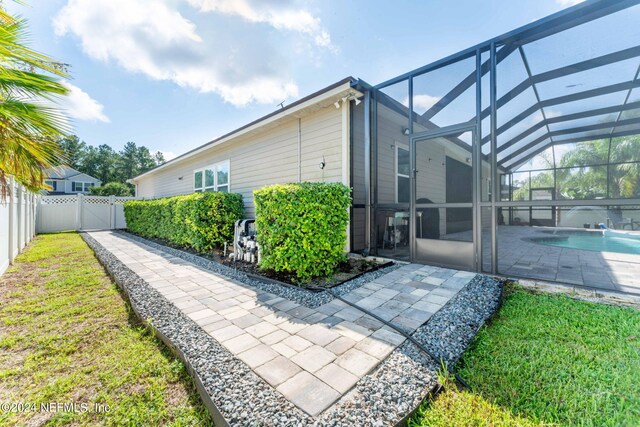 view of home's exterior with a fenced in pool, a lawn, a patio, and a lanai