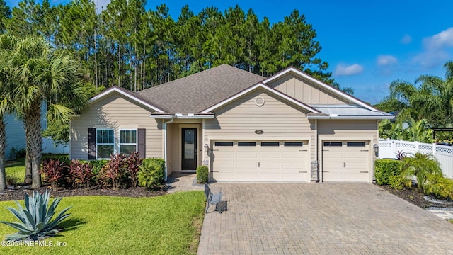 ranch-style home with decorative driveway, an attached garage, board and batten siding, fence, and a front lawn