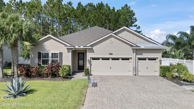 ranch-style home with an attached garage, fence, decorative driveway, board and batten siding, and a front yard