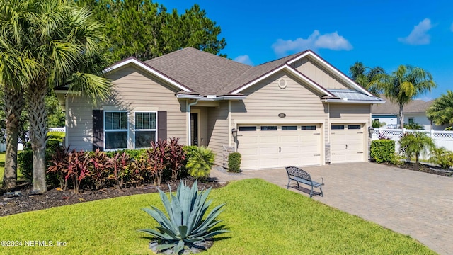 ranch-style home with a garage, a front yard, decorative driveway, and fence