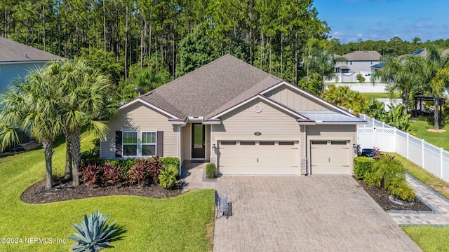 view of front facade with a shingled roof, an attached garage, fence, decorative driveway, and a front yard