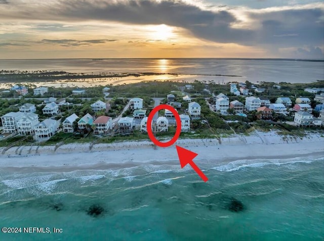 aerial view at dusk with a view of the beach and a water view