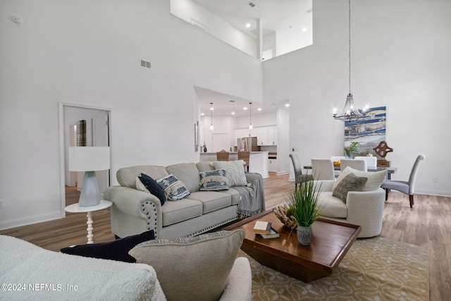 living room featuring a notable chandelier, hardwood / wood-style floors, and a towering ceiling