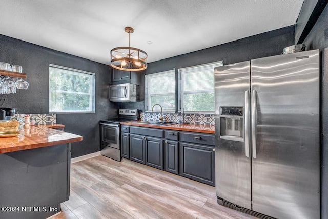 kitchen featuring butcher block counters, a healthy amount of sunlight, stainless steel appliances, and light hardwood / wood-style floors