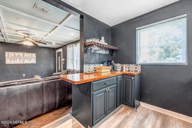 kitchen featuring ceiling fan, wooden counters, light wood-type flooring, and coffered ceiling