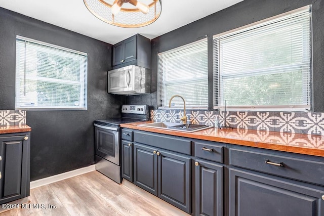 kitchen featuring wooden counters, decorative backsplash, sink, light hardwood / wood-style flooring, and stainless steel range with electric cooktop