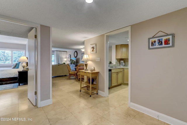 hall with a sink, baseboards, and light tile patterned floors