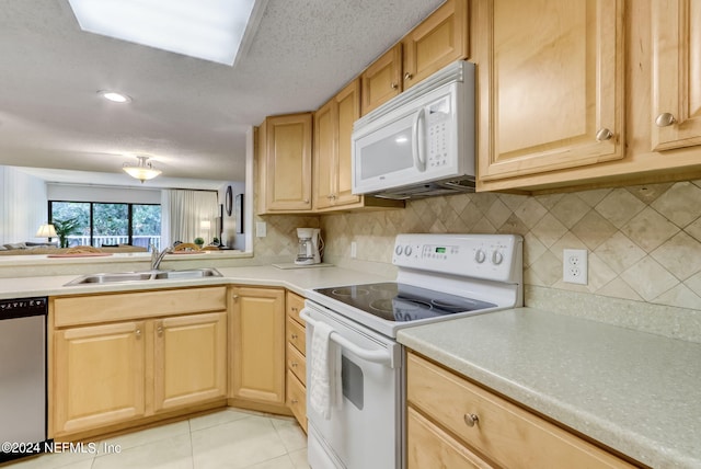 kitchen featuring light brown cabinetry, white appliances, light tile patterned flooring, and a sink