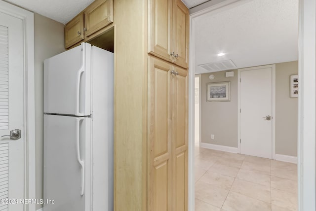 kitchen with light tile patterned floors, visible vents, baseboards, freestanding refrigerator, and a textured ceiling