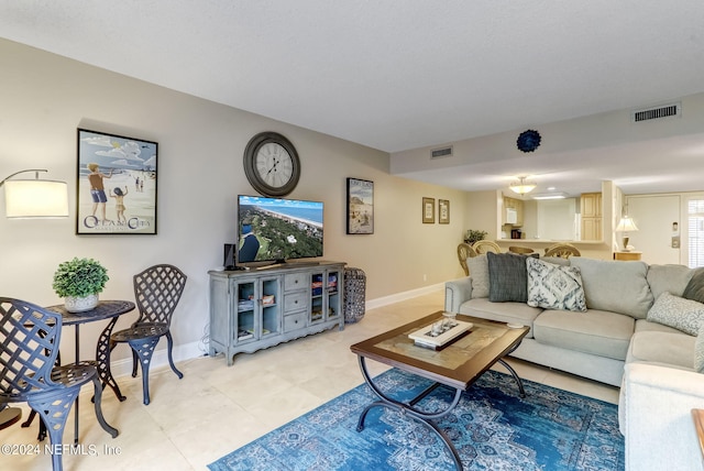 living area with light tile patterned floors, visible vents, and baseboards