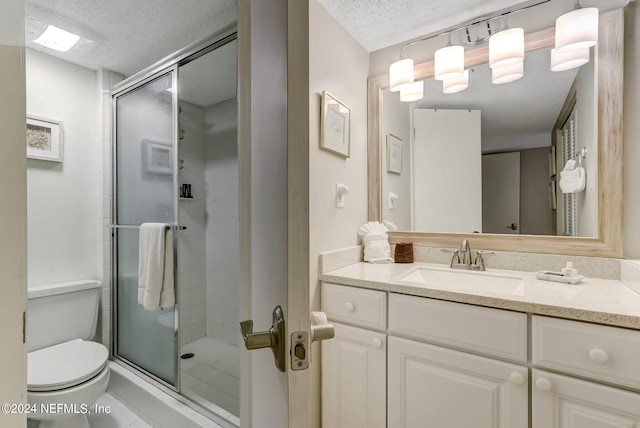 bathroom featuring a textured ceiling, vanity, a shower stall, and toilet