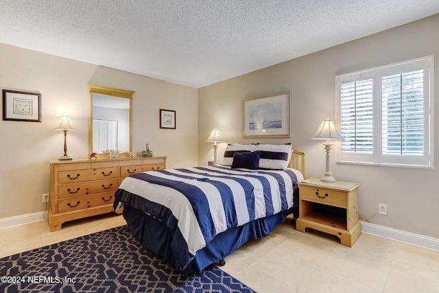 bedroom with light tile patterned flooring, a textured ceiling, and baseboards