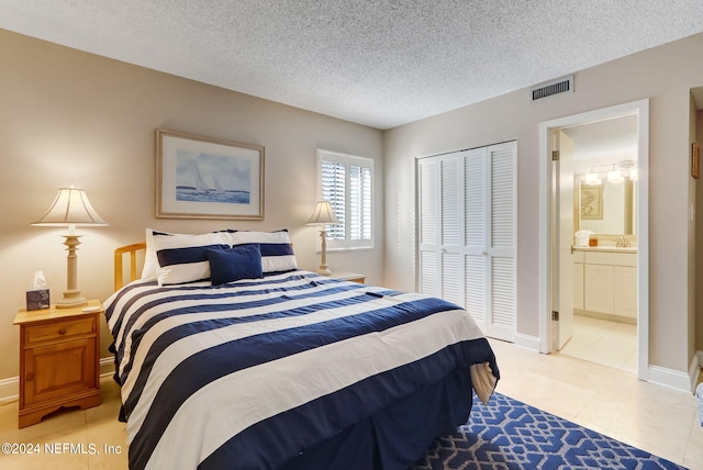 bedroom with light tile patterned floors, a closet, visible vents, a sink, and a textured ceiling