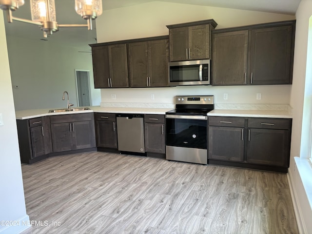 kitchen featuring sink, appliances with stainless steel finishes, dark brown cabinets, light hardwood / wood-style floors, and vaulted ceiling