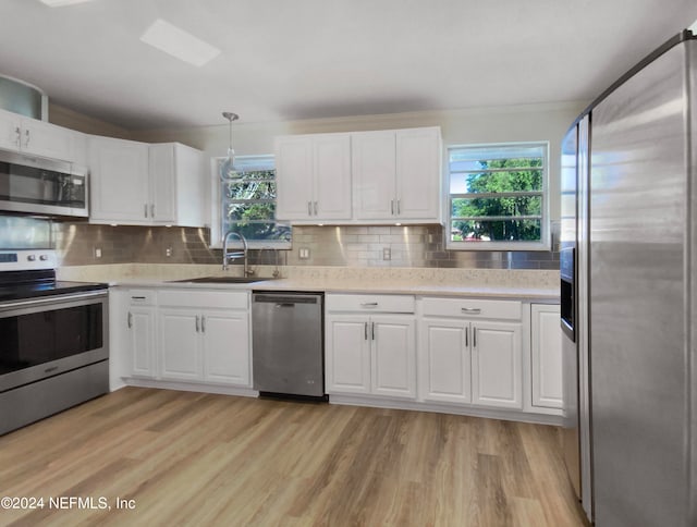 kitchen with light hardwood / wood-style floors, appliances with stainless steel finishes, tasteful backsplash, and plenty of natural light