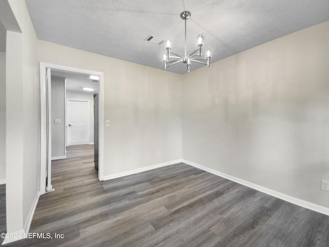 unfurnished dining area featuring dark wood-type flooring, visible vents, a notable chandelier, and baseboards