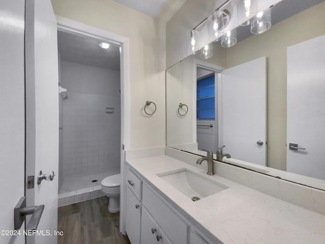 bathroom with toilet, a shower stall, wood finished floors, and vanity