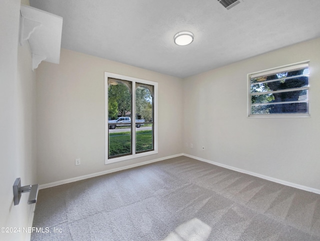 empty room featuring carpet, visible vents, and baseboards