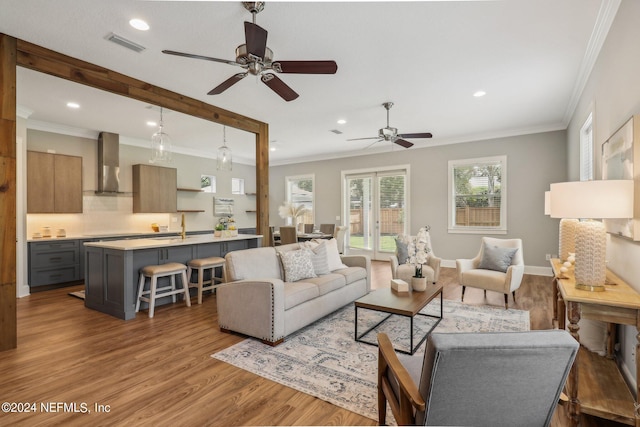 living room featuring ornamental molding, sink, and light hardwood / wood-style floors