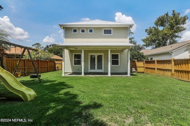 rear view of property featuring a playground, a yard, a patio area, and french doors