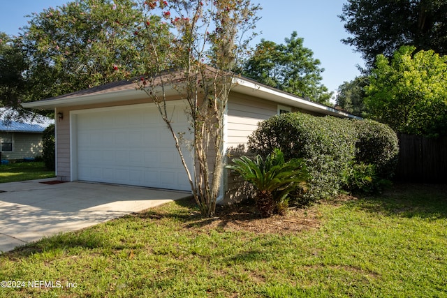 view of side of property featuring a garage and a lawn