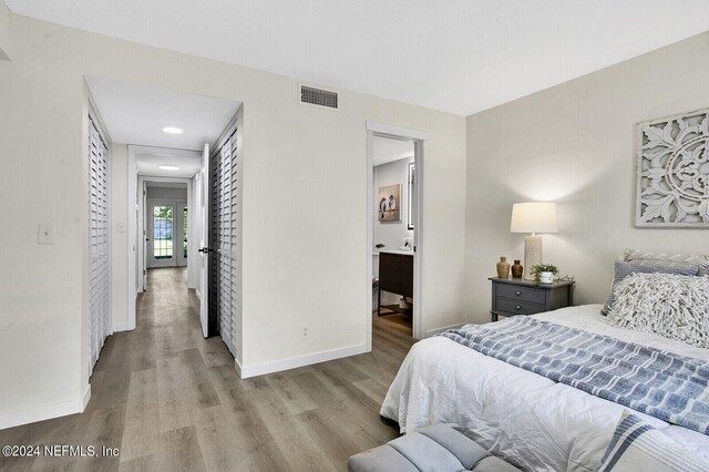 bedroom featuring a closet, connected bathroom, and hardwood / wood-style floors