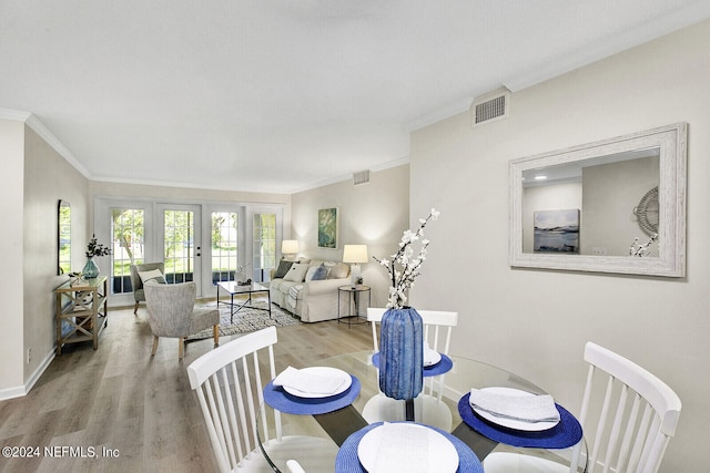 dining room with french doors, crown molding, and light hardwood / wood-style flooring