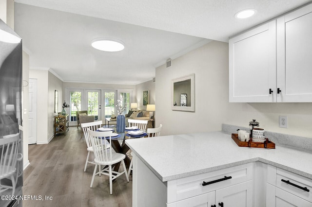 kitchen with crown molding, light hardwood / wood-style floors, kitchen peninsula, and white cabinets