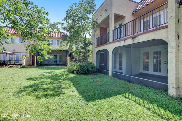 view of yard featuring a balcony and a sunroom