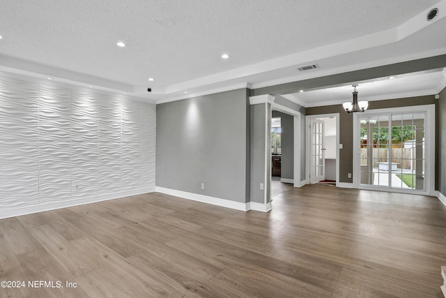 unfurnished living room with hardwood / wood-style flooring, crown molding, an inviting chandelier, and a textured ceiling